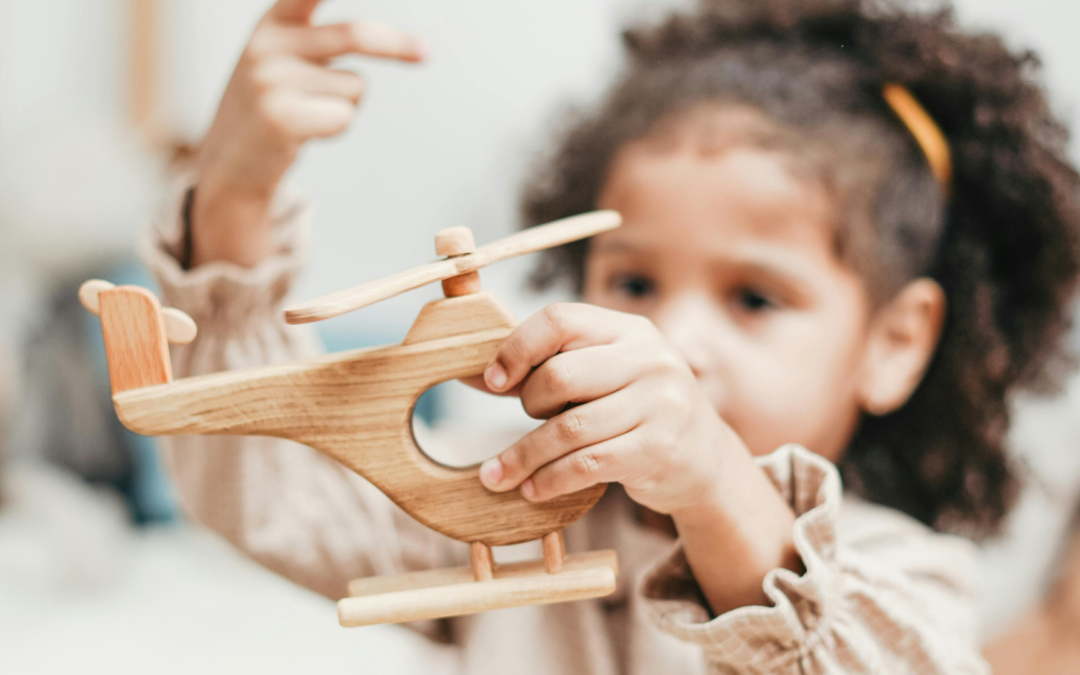child playing with wooden helicopter toy