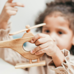 child playing with wooden helicopter toy